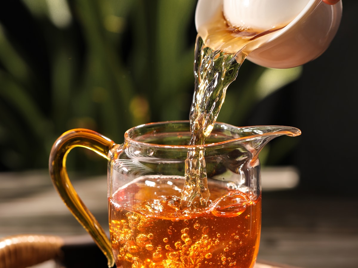Amber tea being poured into a glass server